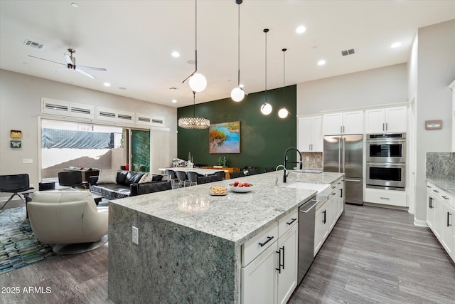 kitchen with visible vents, appliances with stainless steel finishes, a sink, and wood finished floors