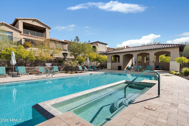 view of pool with fence, a patio area, and a pool with connected hot tub