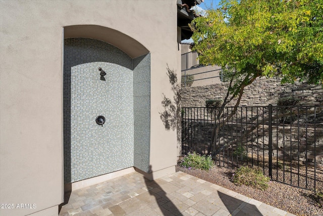 property entrance featuring fence and stucco siding