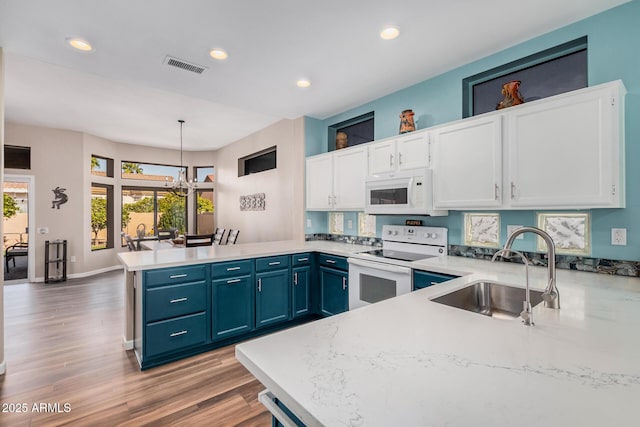 kitchen with white cabinetry, pendant lighting, white appliances, and kitchen peninsula