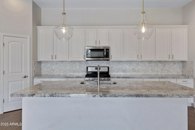 kitchen featuring stainless steel appliances, hanging light fixtures, a center island with sink, and white cabinets