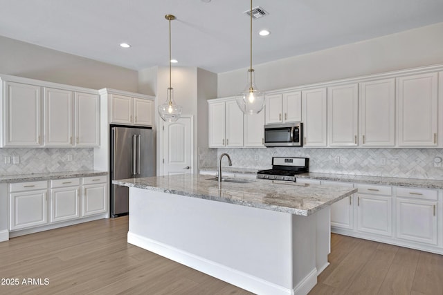 kitchen featuring an island with sink, appliances with stainless steel finishes, sink, and white cabinets