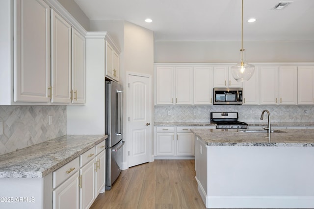 kitchen with pendant lighting, stainless steel appliances, light stone countertops, white cabinets, and light wood-type flooring