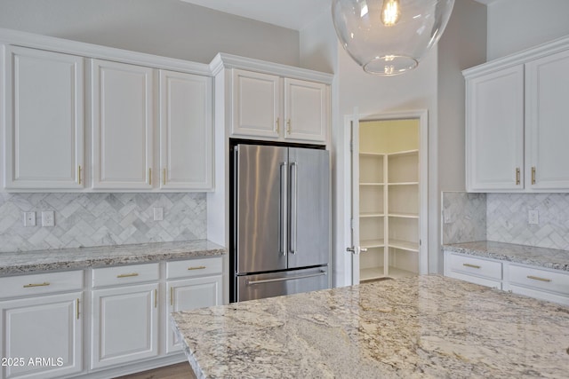 kitchen with white cabinetry, light stone countertops, and stainless steel fridge