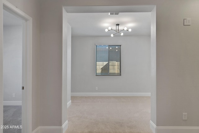 carpeted empty room with an inviting chandelier