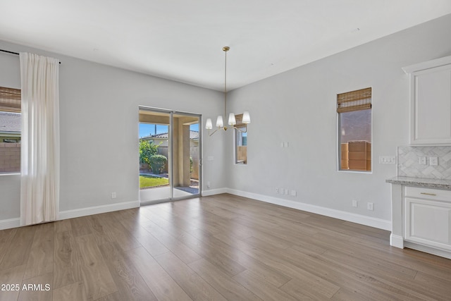 unfurnished dining area featuring a chandelier and light wood-type flooring