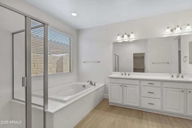 bathroom featuring hardwood / wood-style flooring, vanity, and shower with separate bathtub