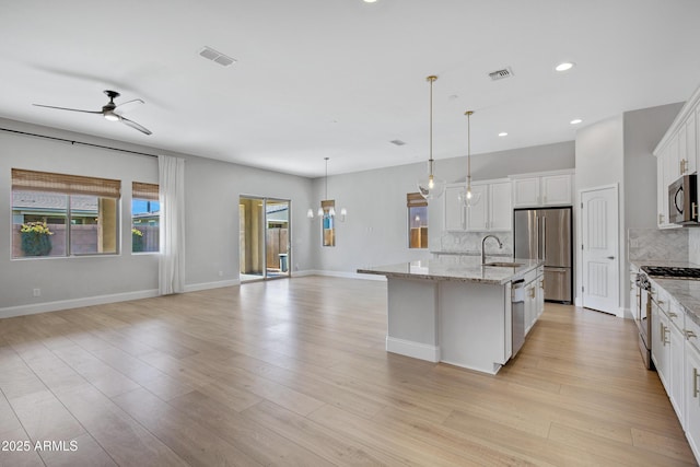 kitchen featuring sink, white cabinetry, hanging light fixtures, high end appliances, and an island with sink