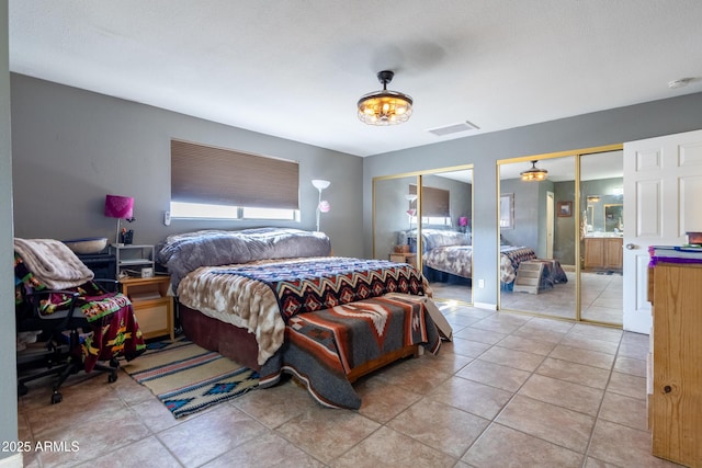 tiled bedroom featuring two closets