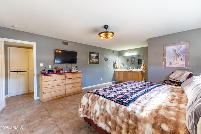 bedroom featuring ensuite bathroom and light tile patterned floors