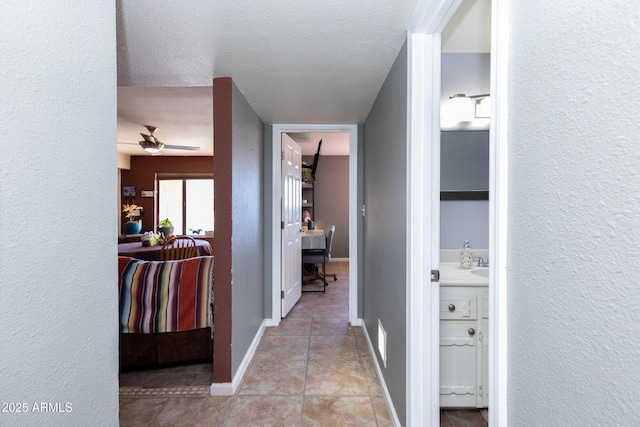 hall featuring a textured ceiling and light tile patterned floors