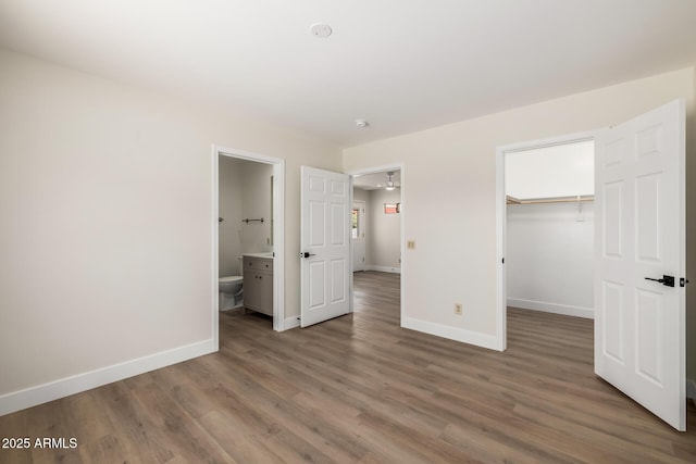 13601 N 50th Pl, Scottsdale, AZ 85254 - unfurnished bedroom with wood finished floors, baseboards, a spacious closet, a closet, and connected bathroom