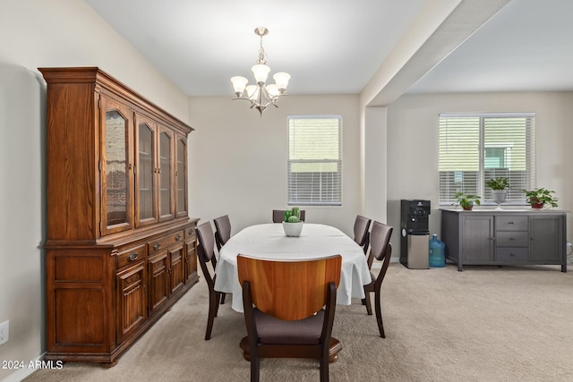 dining space with an inviting chandelier, a healthy amount of sunlight, and light colored carpet