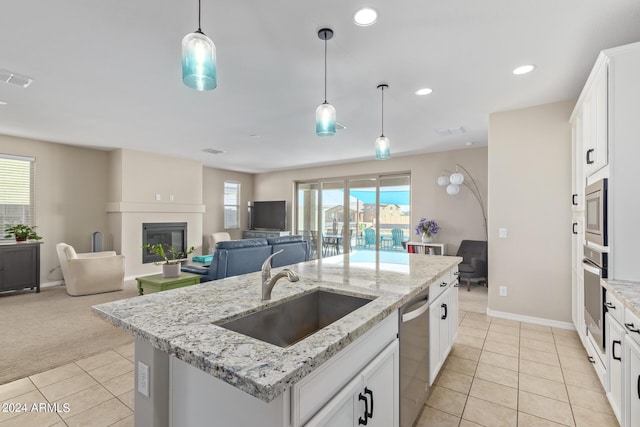 kitchen with a fireplace, sink, white cabinetry, an island with sink, and stainless steel appliances