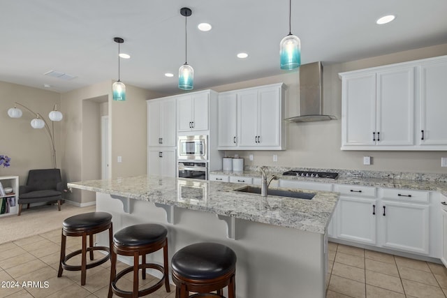 kitchen featuring appliances with stainless steel finishes, sink, a center island with sink, and wall chimney range hood