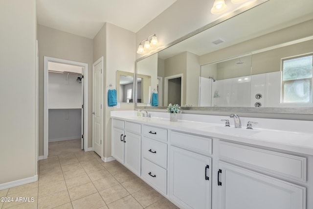 bathroom with a shower, tile patterned flooring, and vanity