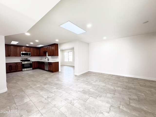 kitchen featuring dark brown cabinets, sink, stainless steel appliances, and a skylight