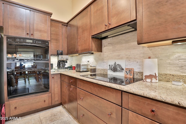 kitchen with light stone counters, ventilation hood, black appliances, and tasteful backsplash