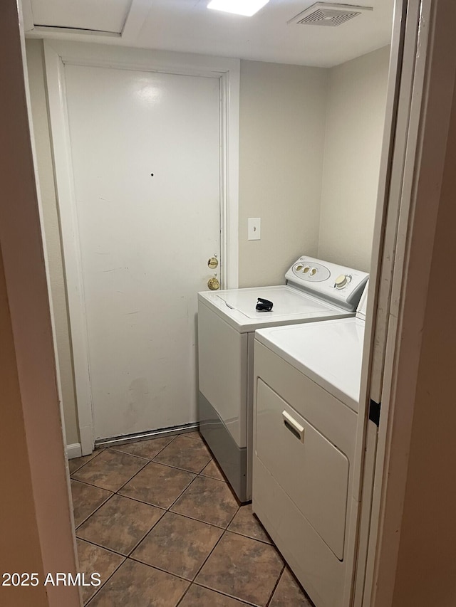 clothes washing area featuring washer and clothes dryer and dark tile patterned floors