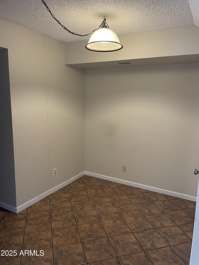 tiled empty room featuring a textured ceiling