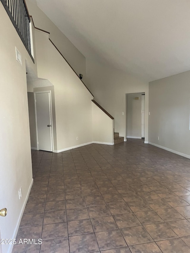 unfurnished room with dark tile patterned floors and a towering ceiling