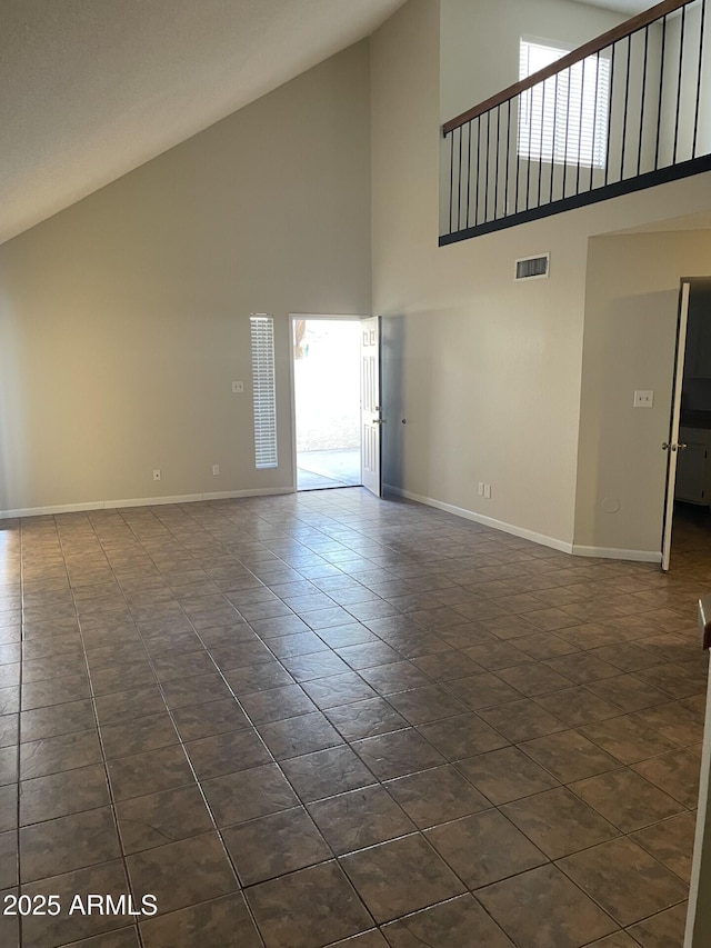 empty room featuring dark tile patterned floors and high vaulted ceiling