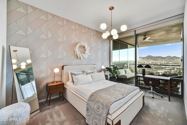 carpeted bedroom with a mountain view, access to outside, and an inviting chandelier