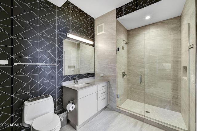 bathroom featuring toilet, vanity, tile walls, and a shower with door