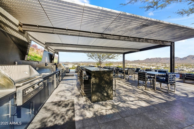 view of patio / terrace with an outdoor kitchen, an outdoor bar, a mountain view, and grilling area