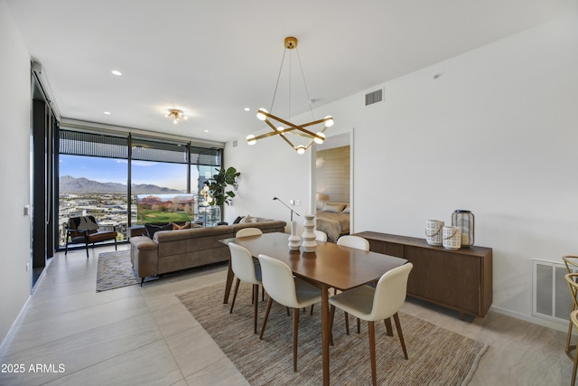 dining area with a mountain view, a wall of windows, and a chandelier