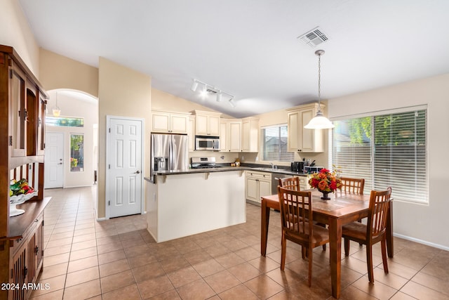 kitchen featuring rail lighting, light tile patterned floors, cream cabinetry, decorative light fixtures, and stainless steel appliances