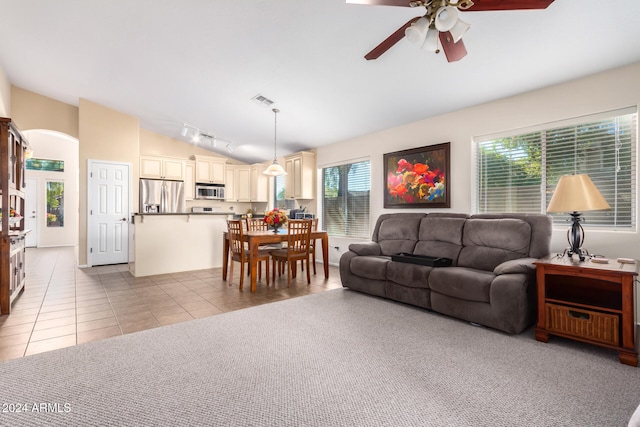 tiled living room featuring ceiling fan and vaulted ceiling