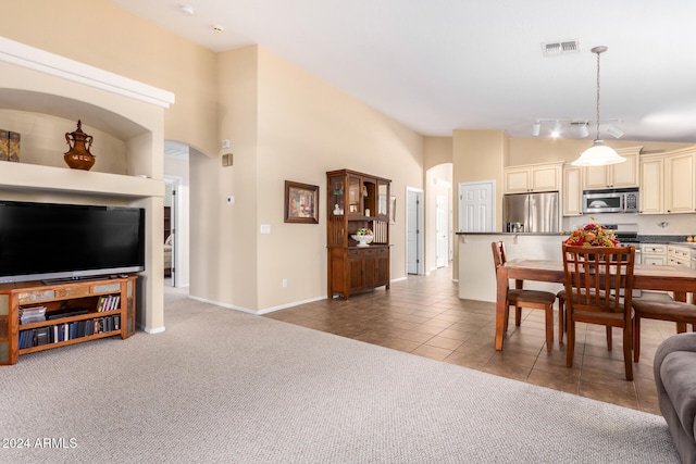 dining room with light carpet and high vaulted ceiling