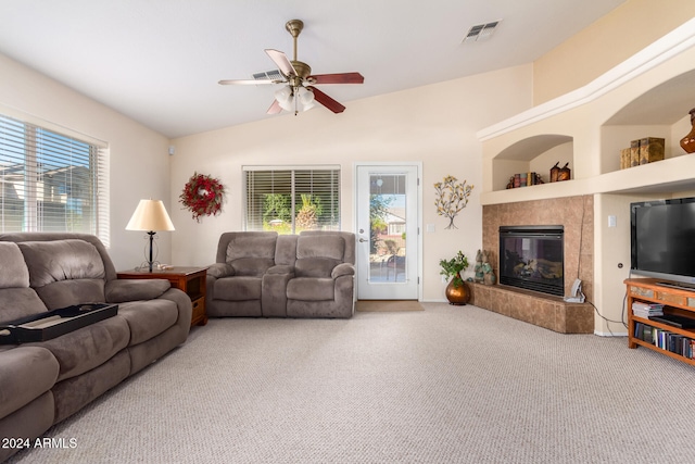 carpeted living room with a tiled fireplace, ceiling fan, and lofted ceiling