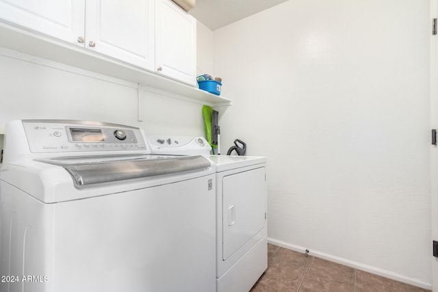 clothes washing area featuring cabinets, dark tile patterned floors, and washer and dryer