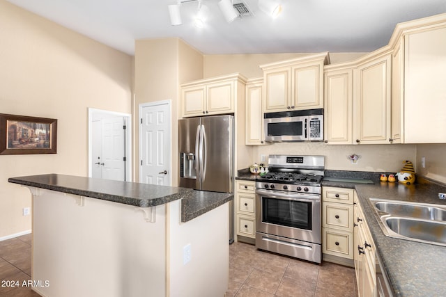 kitchen with a breakfast bar area, cream cabinets, vaulted ceiling, and appliances with stainless steel finishes