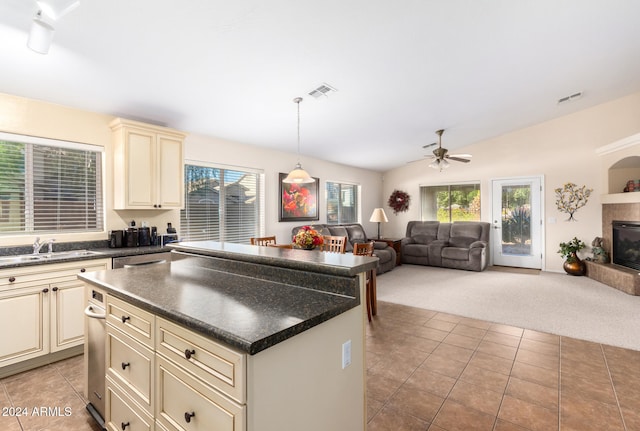 kitchen with ceiling fan, cream cabinets, pendant lighting, light colored carpet, and lofted ceiling