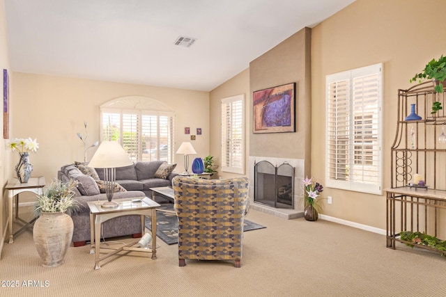 living room featuring lofted ceiling, visible vents, a fireplace with raised hearth, baseboards, and carpet