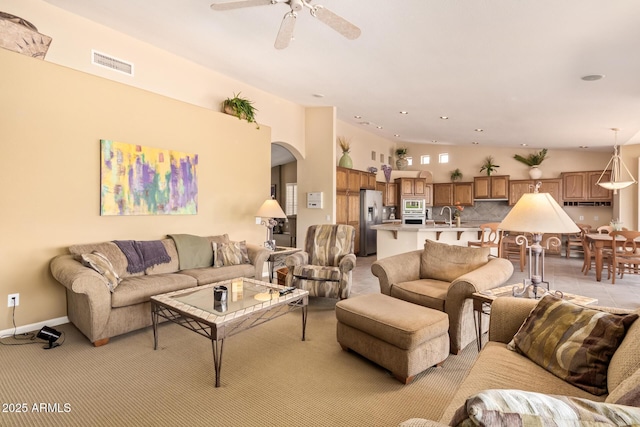 living room with visible vents, arched walkways, and ceiling fan
