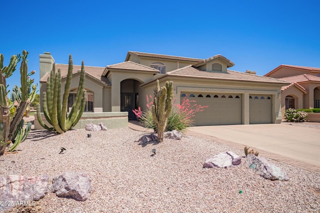 mediterranean / spanish-style home featuring a tiled roof, stucco siding, concrete driveway, and an attached garage