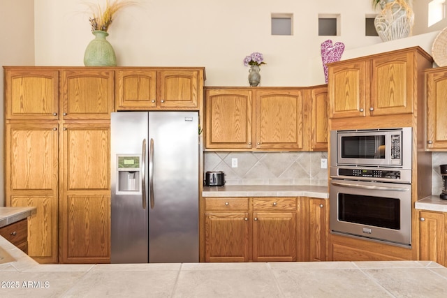 kitchen featuring stainless steel appliances, decorative backsplash, and brown cabinetry