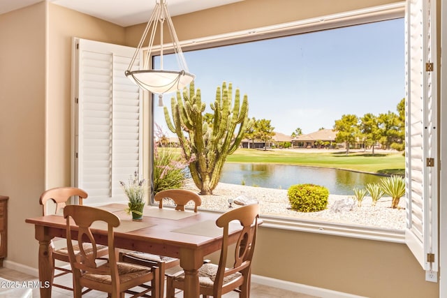 dining area with baseboards and a water view