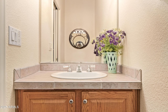 bathroom with a textured wall and vanity