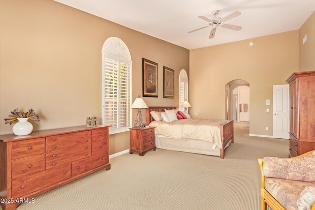 bedroom featuring baseboards, arched walkways, a ceiling fan, and carpet