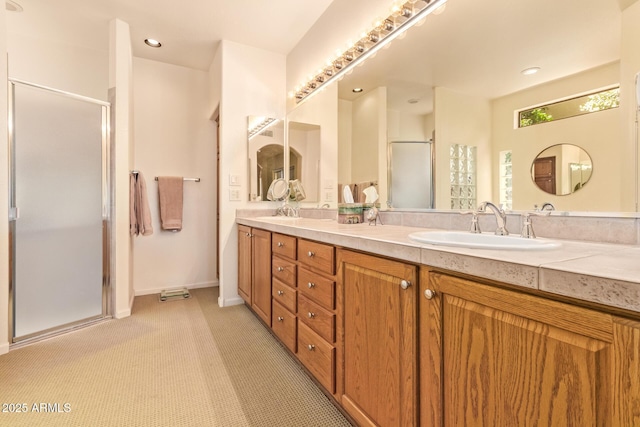 bathroom featuring double vanity, baseboards, a stall shower, and a sink