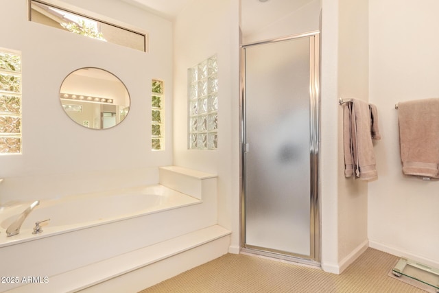 bathroom with a garden tub, a stall shower, and baseboards