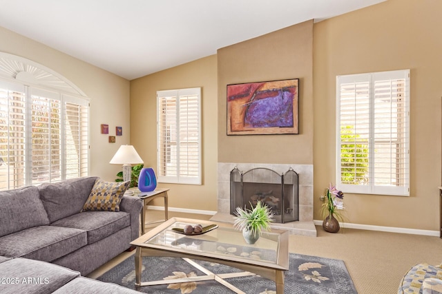living room featuring lofted ceiling, carpet, a tiled fireplace, and baseboards