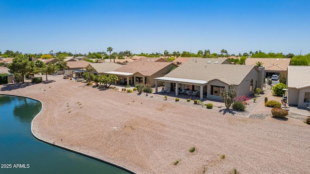 rear view of property featuring stucco siding, a residential view, a water view, and a patio area