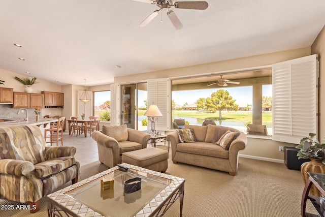 living area with light colored carpet, a ceiling fan, and vaulted ceiling