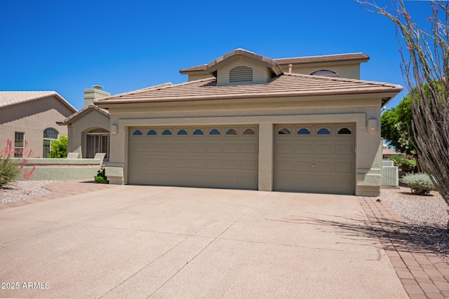 mediterranean / spanish-style home featuring a chimney, stucco siding, a tiled roof, driveway, and an attached garage